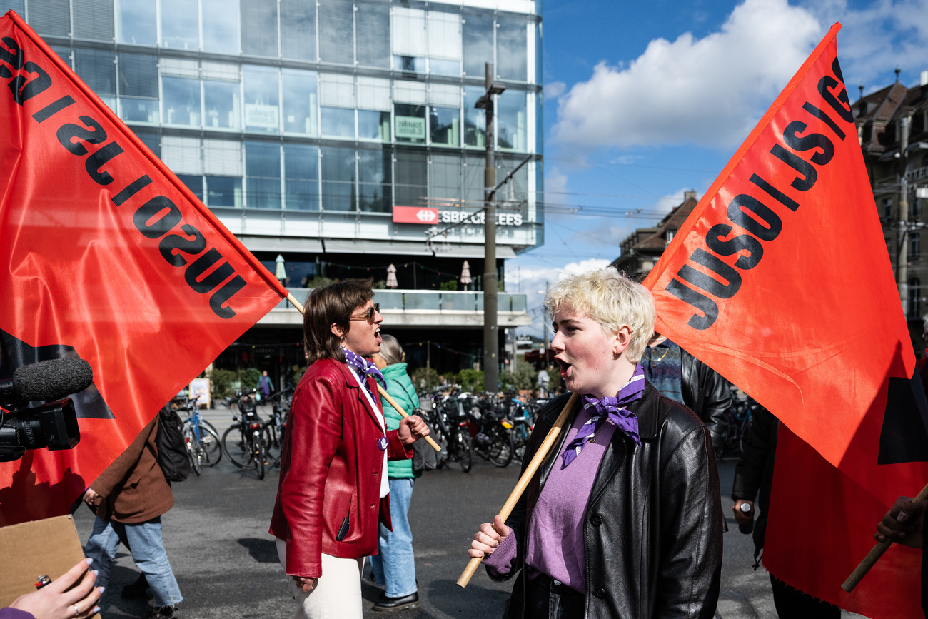 Two women carry flags calling for justice for women in Switzerland