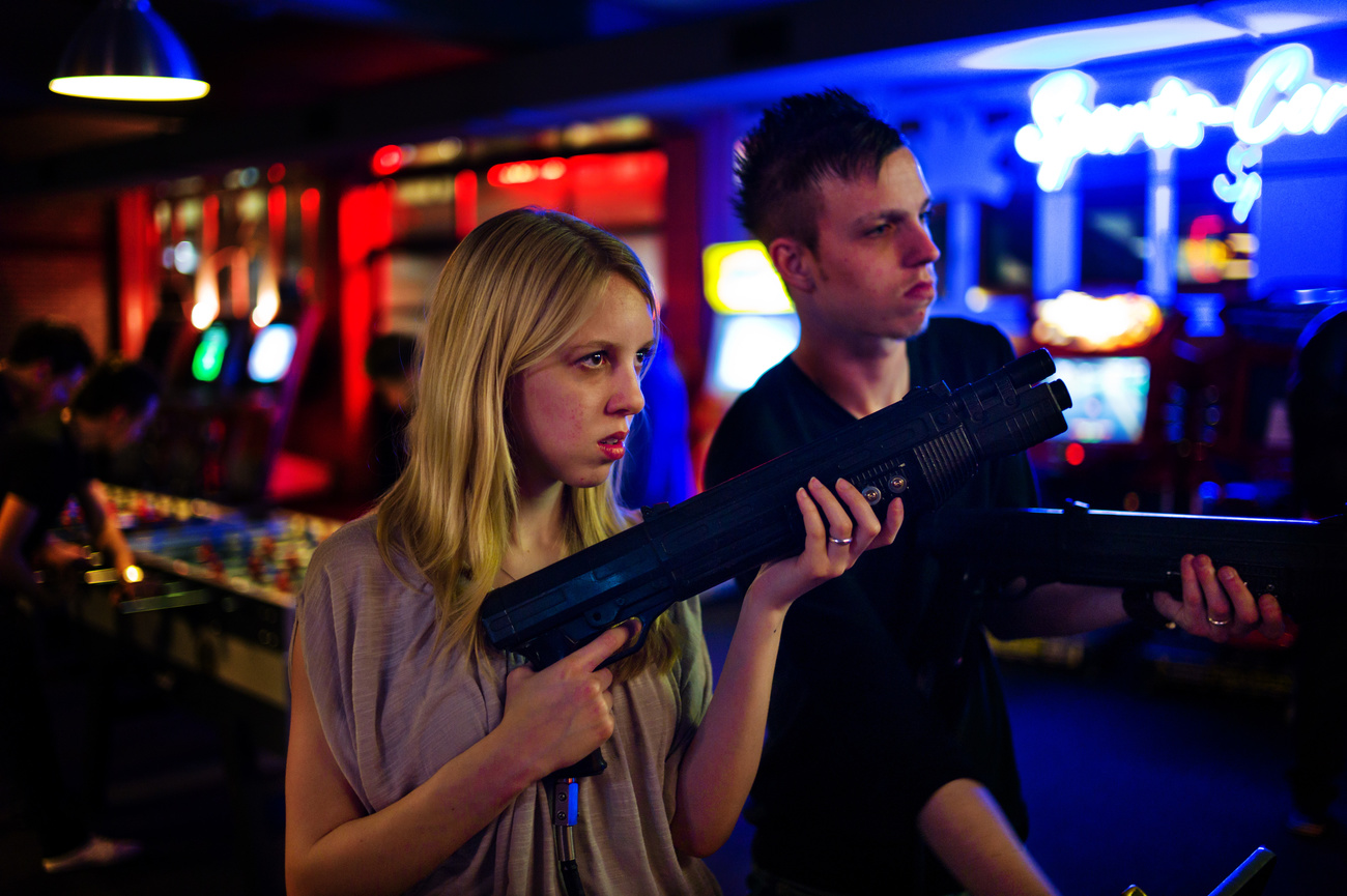 due adolescenti maschio e femmina giocano in una sala giochi con un arma giocattolo