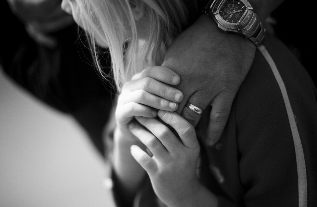 foto in bianco e nero di bambina bionda che tiene la mano del papà con entrambe le mani