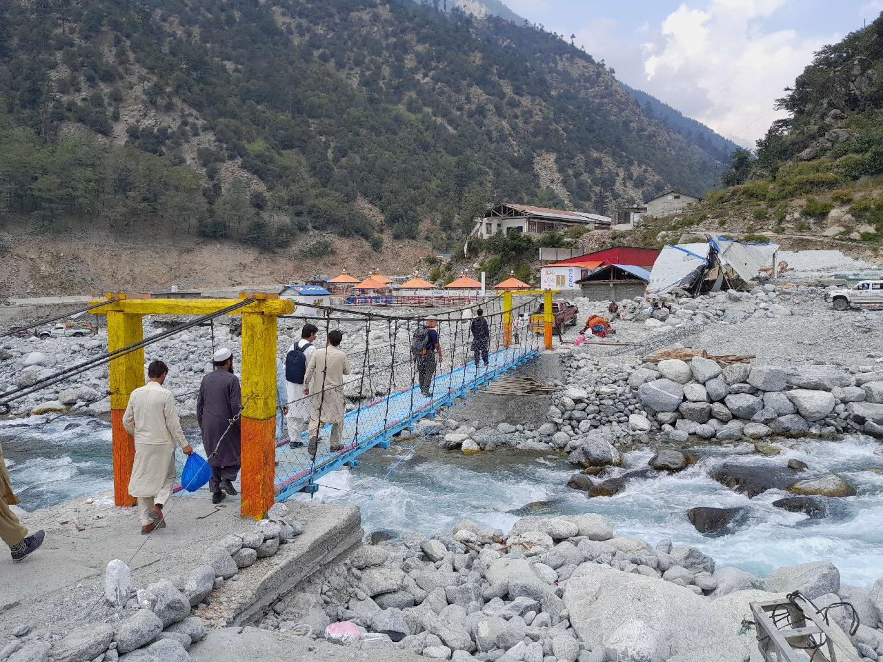 أشخاص يعبرون جسرا مؤقتا في باكستان