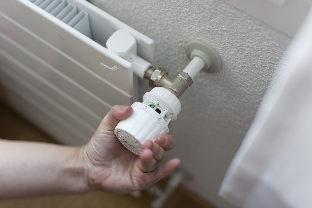 Person turns down thermostat on radiator