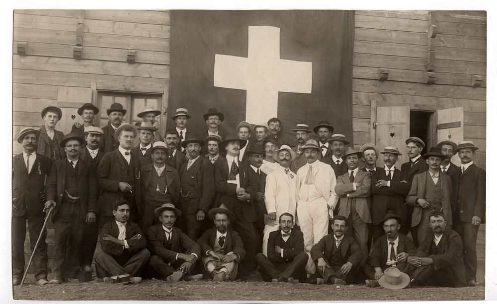 Groupe d homme devant un chalet et un drapeau suisse