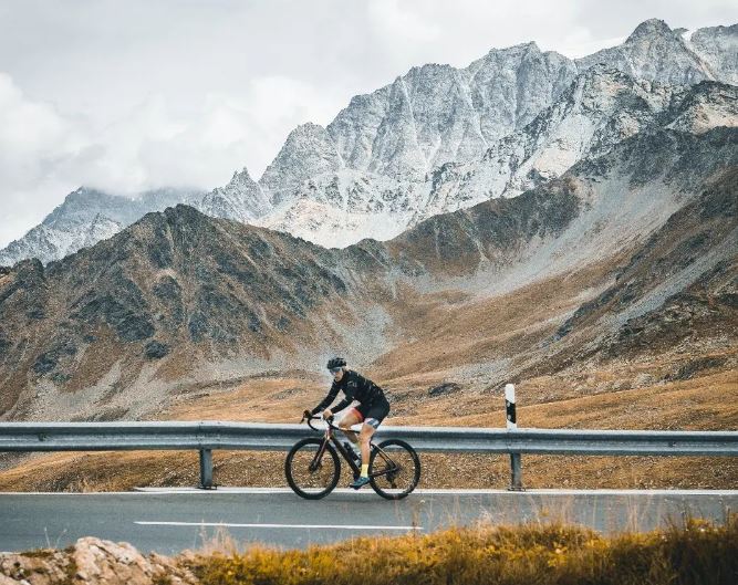 Frau fährt auf dem Rennvelo einen Pass in den Alpen hoch