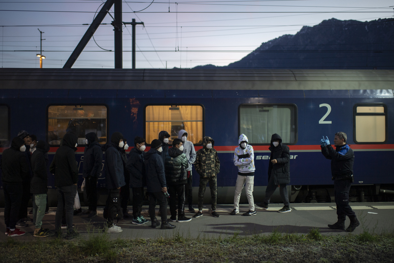 Gruppe von geflüchteten und Polizei vor einem Zug in einem schweizer bahnhof