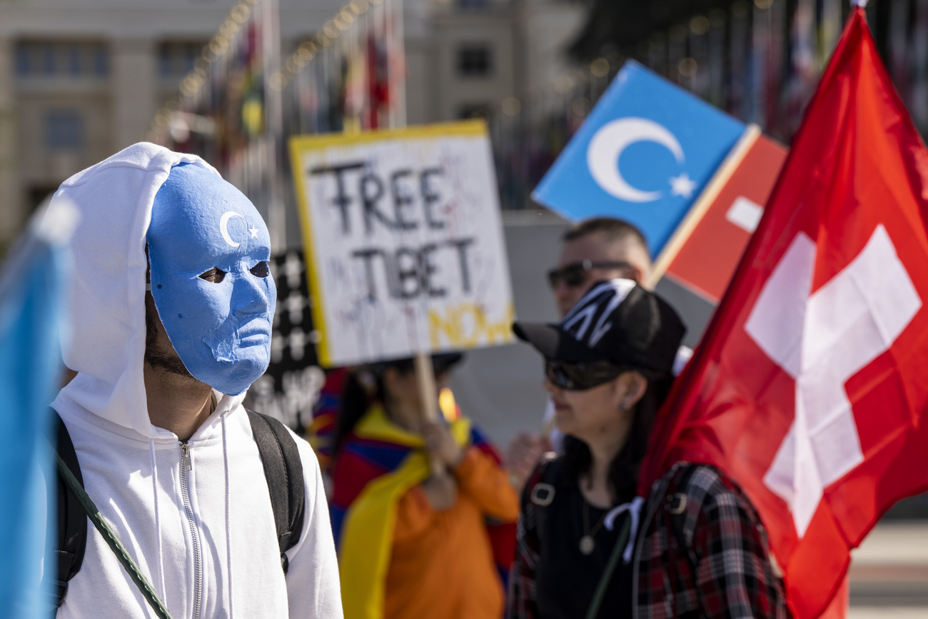 متظاهرون يرتدون أقنعة ويرفعون أعلام سويسرا وتركستان الشرقية
