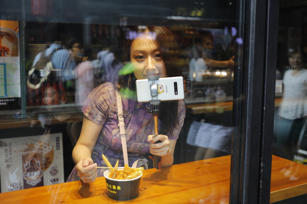 Une touriste chinoise prend un selfie en mangeant ses frites
