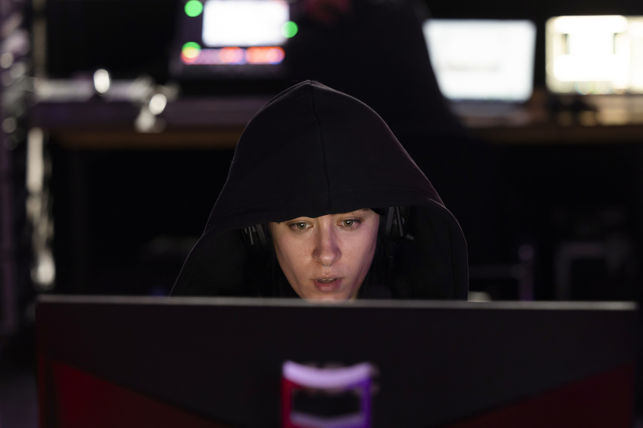 ragazza con cappuccio nero dietro a schermo di computer