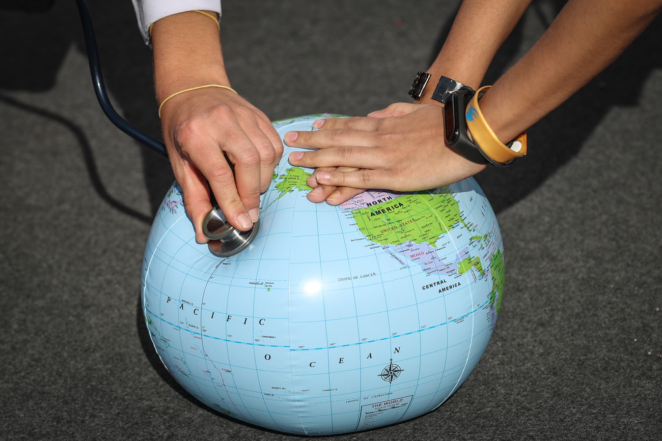 una pelota del globo terrestre y una mano de un médico auscultando la Tierra