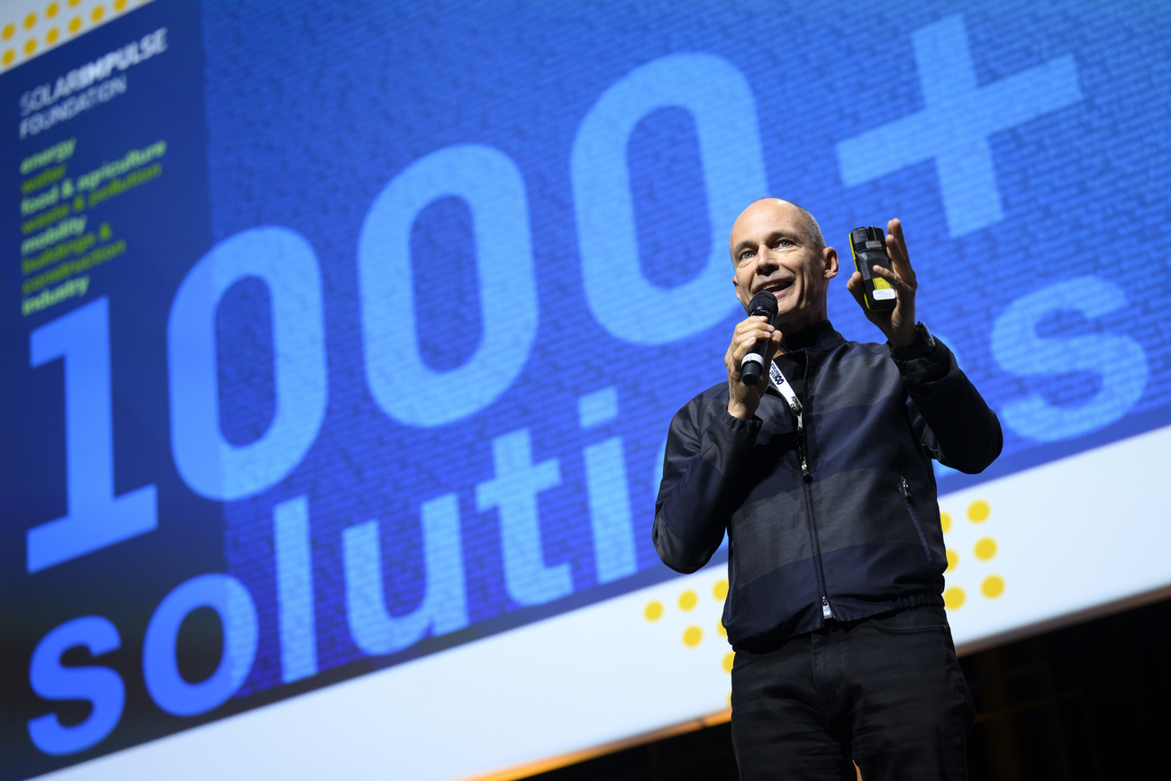 Man giving a talk with words 1,000+ solutions on screen behind him