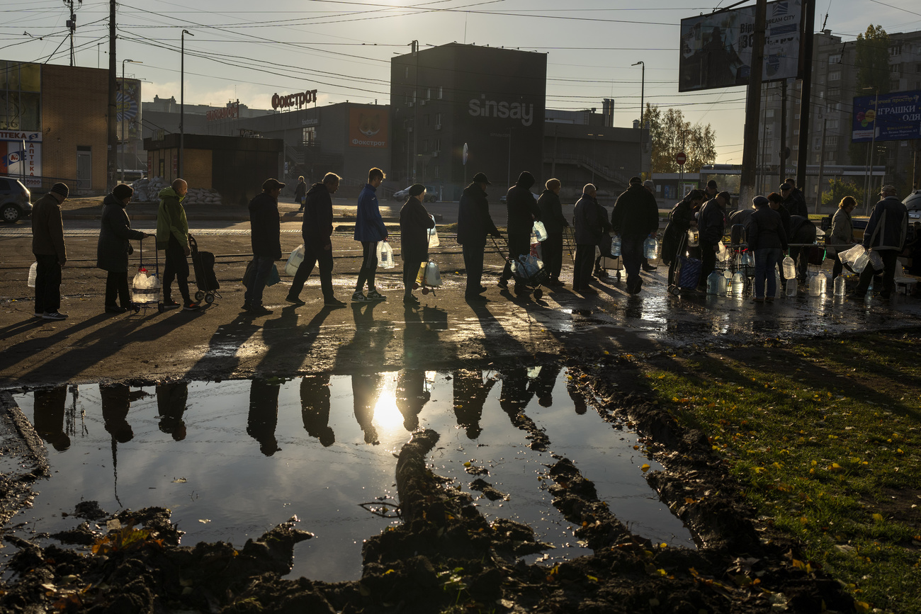 People queue up to refill drinking water bottles from a tank in the centre of Mykolaiv, October 24, 2022. 