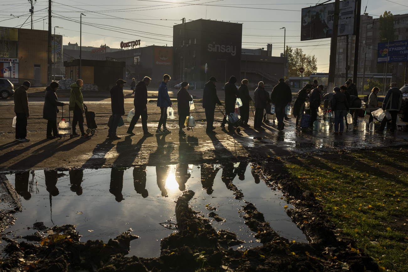 As pessoas fazem fila para reabastecer garrafas de água potável de um tanque no centro de Mykolaiv, 24 de outubro de 2022.