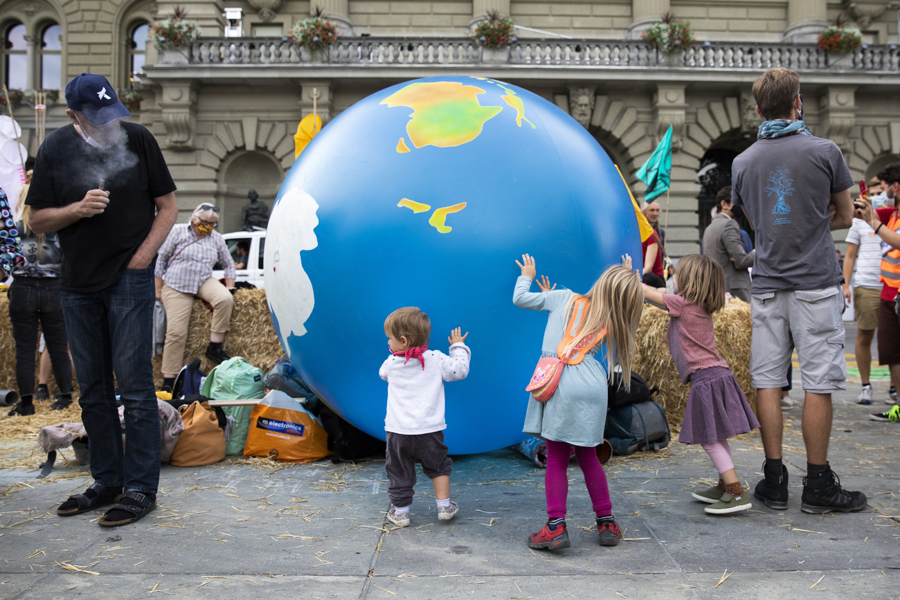 Bambini sorreggono un globo terrestre gigante sulla Piazza Federale.
