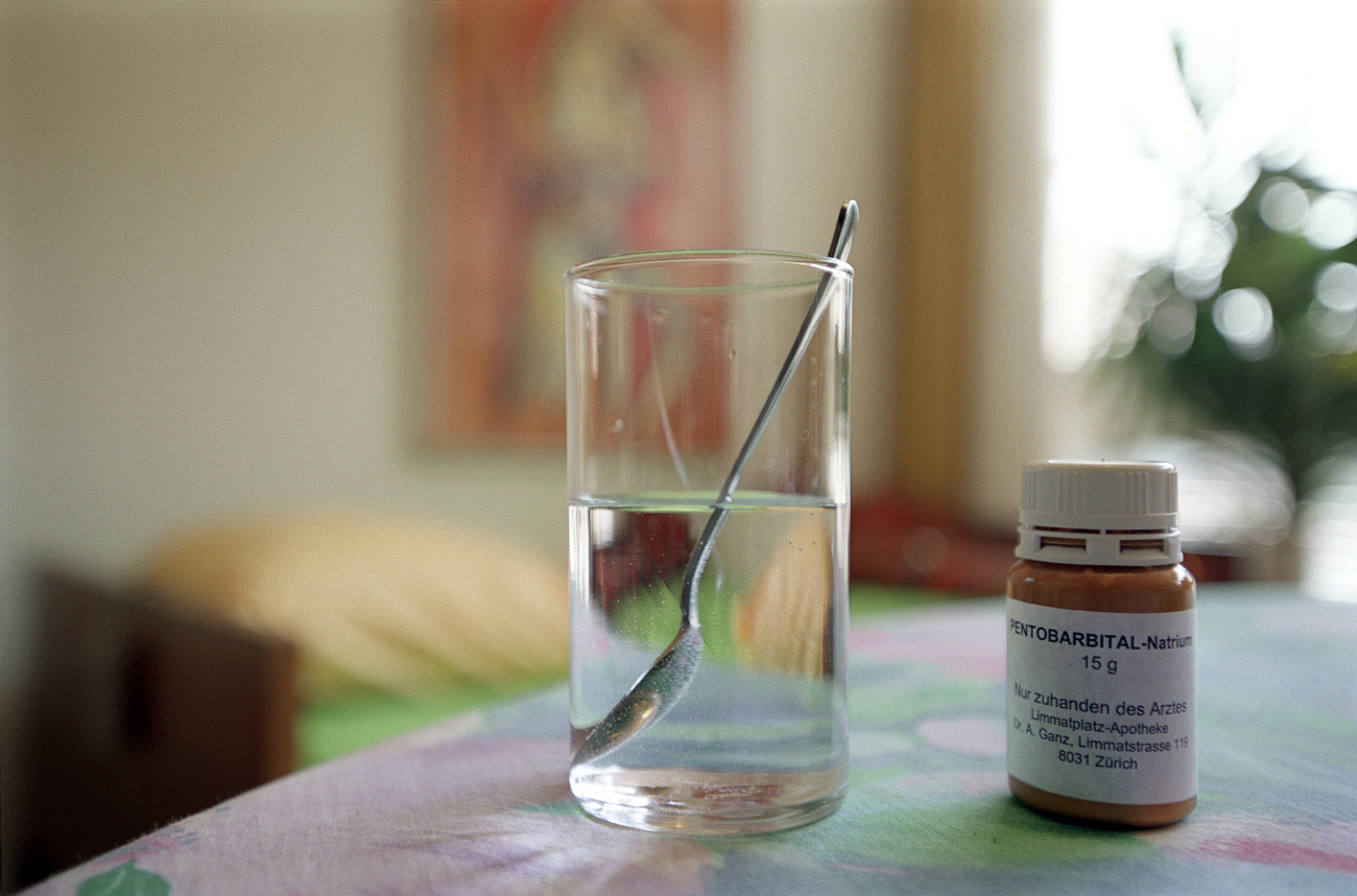 Un vaso de agua y un medicamento sobre una mesa.