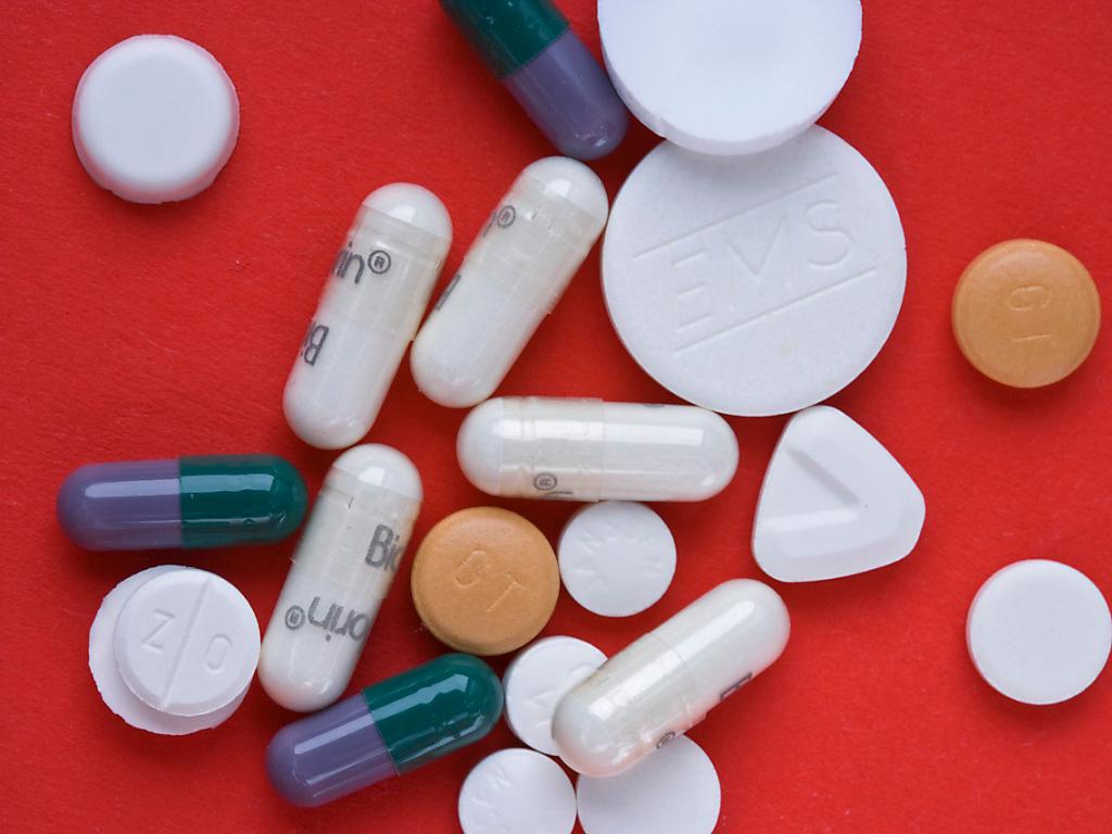viele Tabletten und Pillen auf einem roten Untergrund