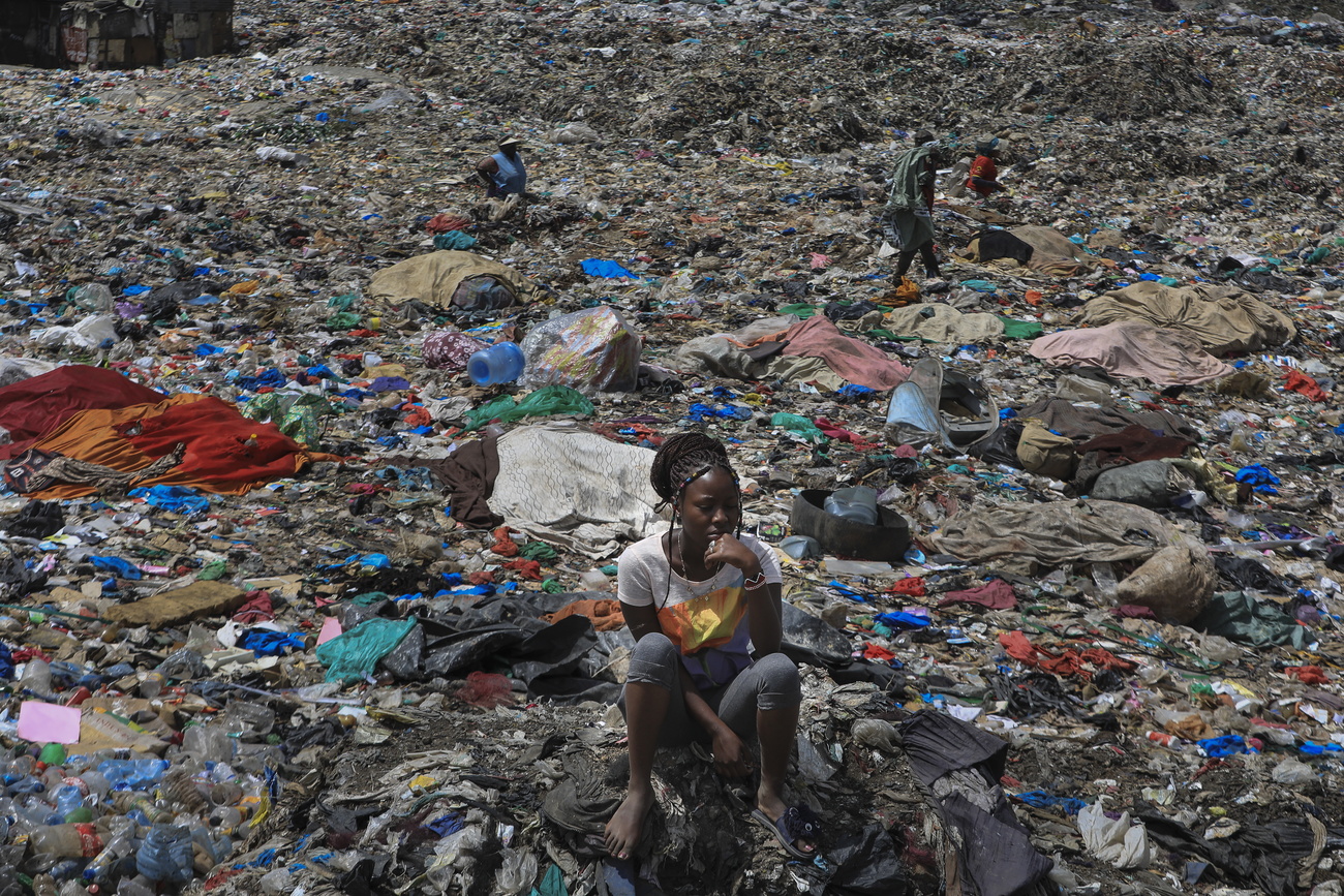 Jeune fille assise dans les détritus, dans la décharge de Dandora au Kenya.