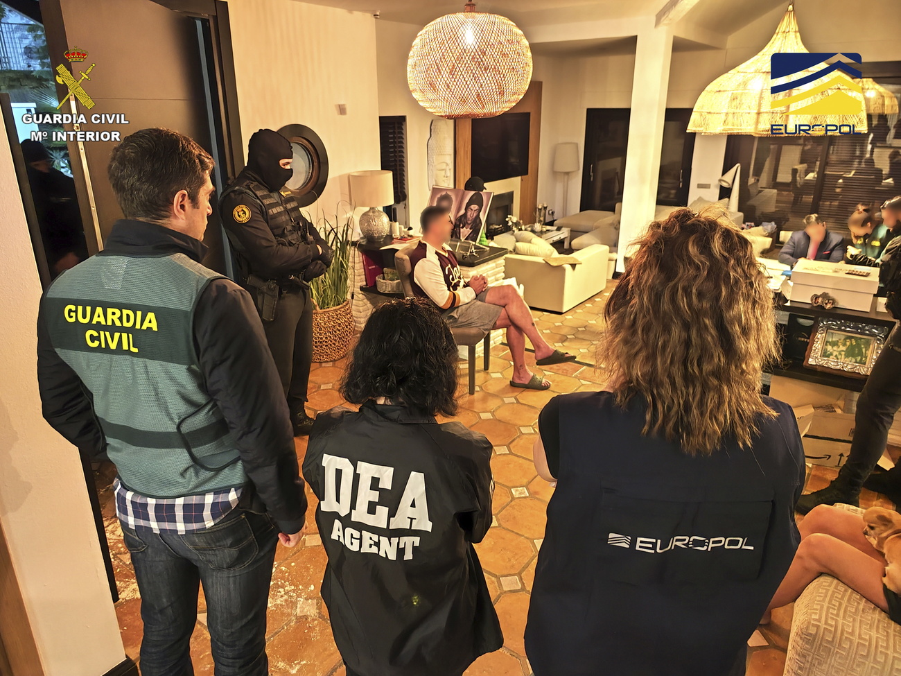 agenti fotografati di spalle osservano appartamento di uno degli arrestati