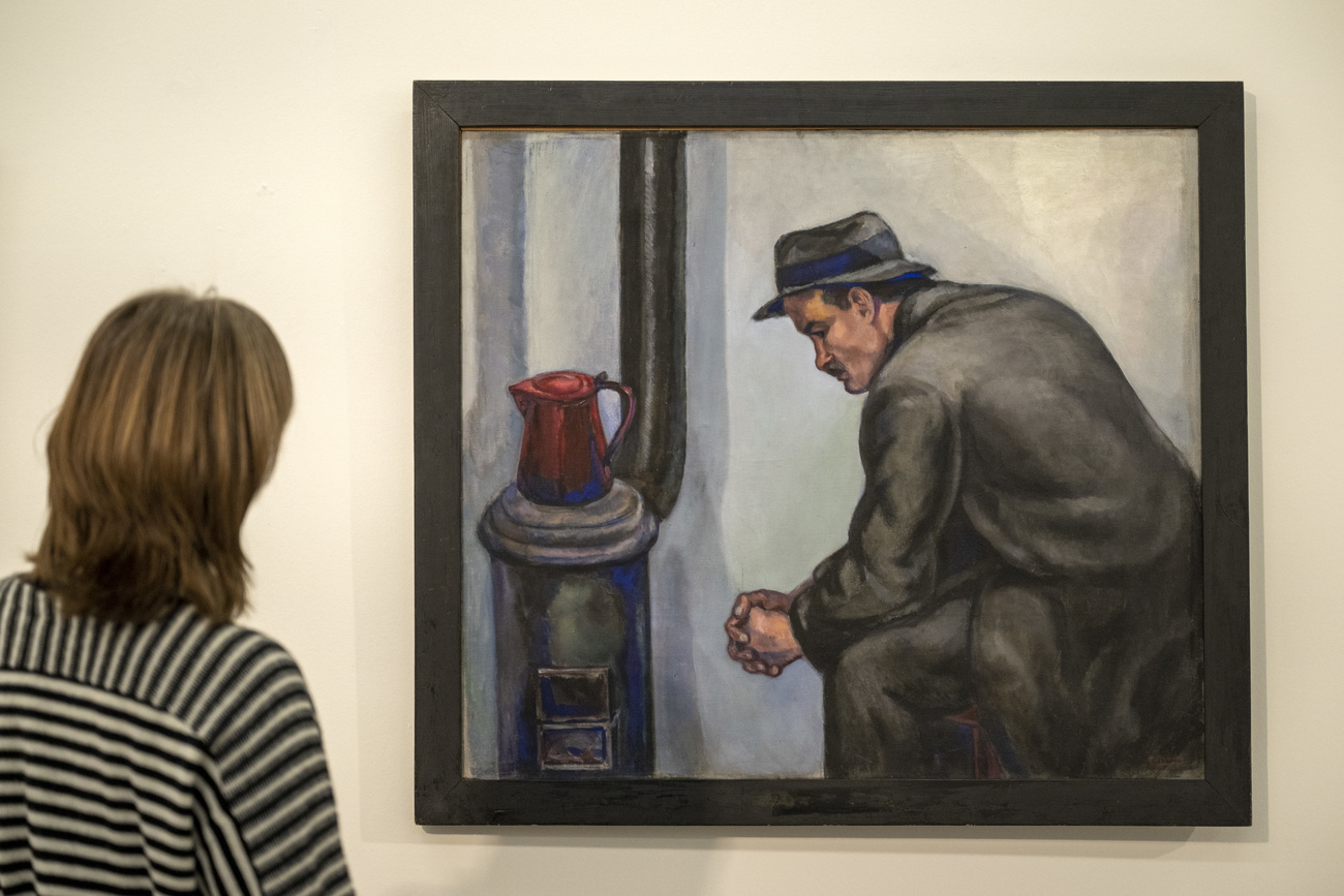 Una mujer contempla el cuadro de un hombre sentado frente a una chimenea