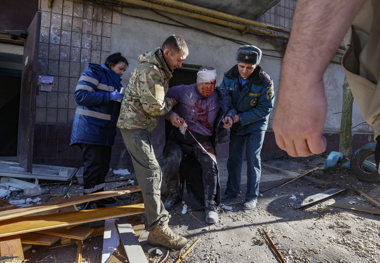 Homem ferido sendo ajudado a partir de um prédio em Donetsk, Ucrânia