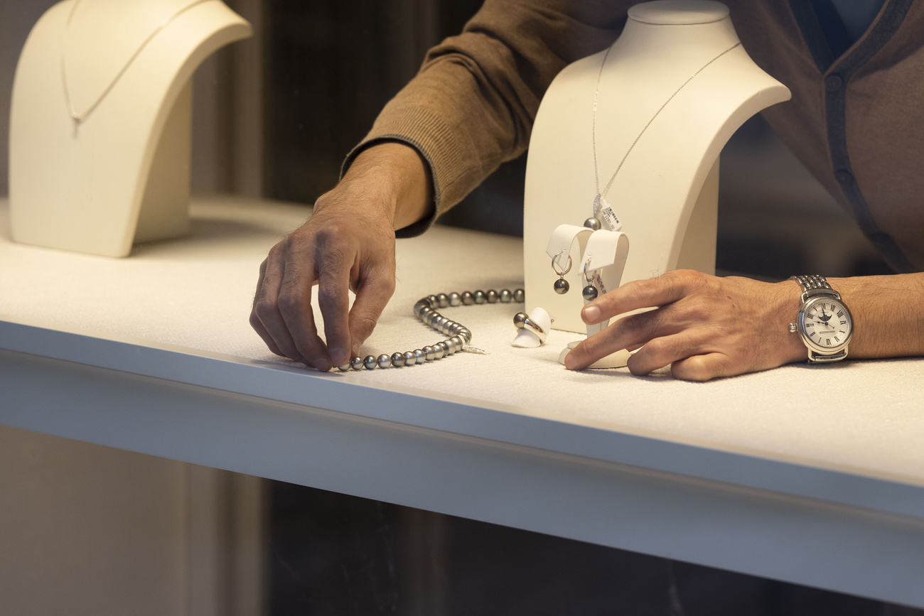 Vitrina de joyería. Una mujer coloca un collar.