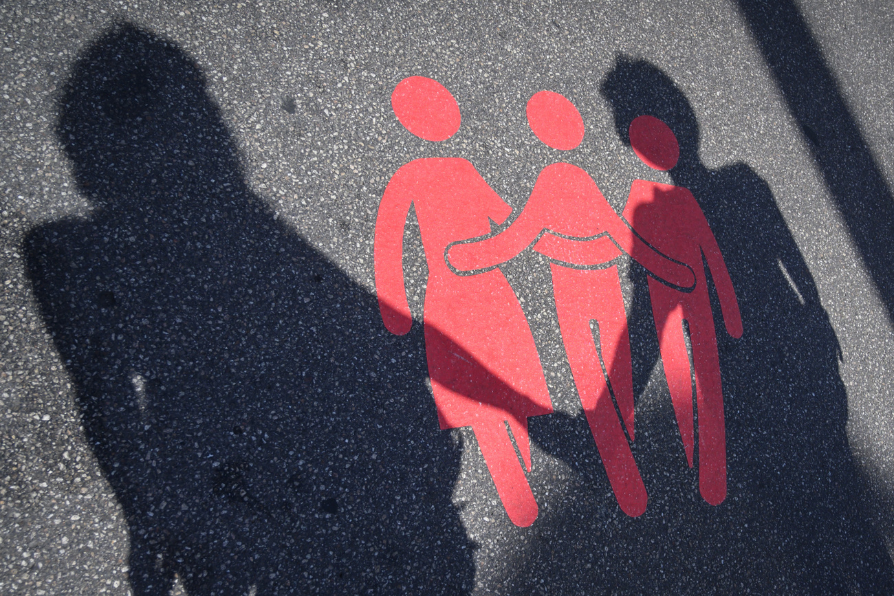 Imagen simbólica de sombre de una pareja en una calle y tres figuras pintadas en el pavimento