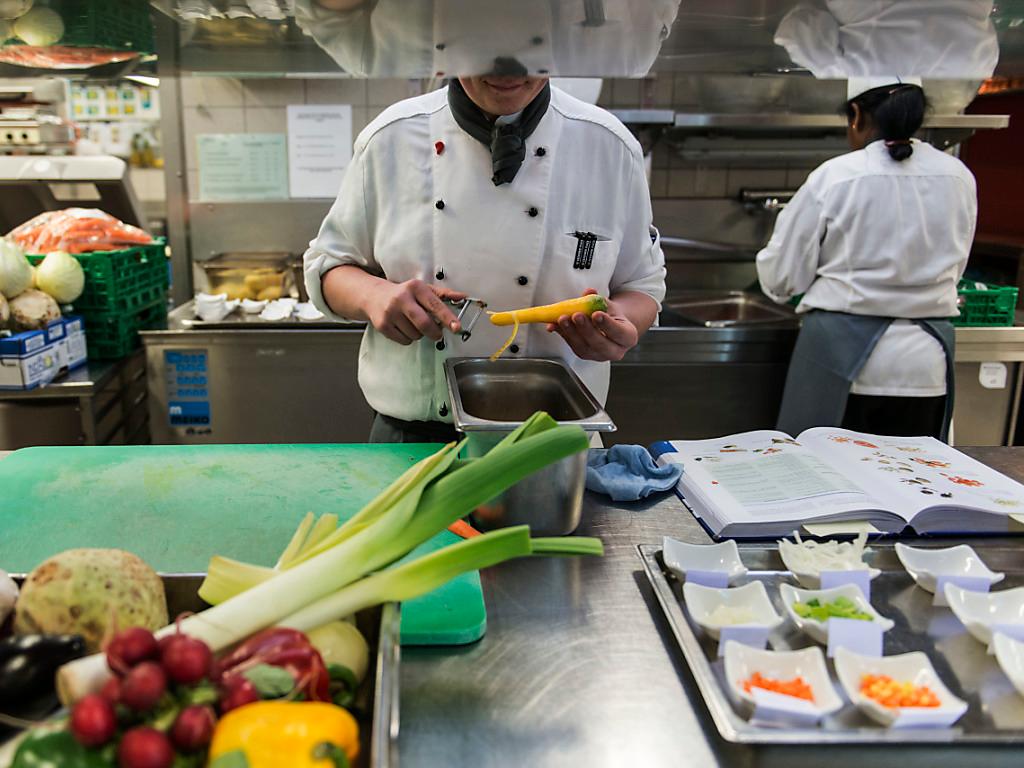 Koch schält eine Karotte in der Küche eines Restaurants