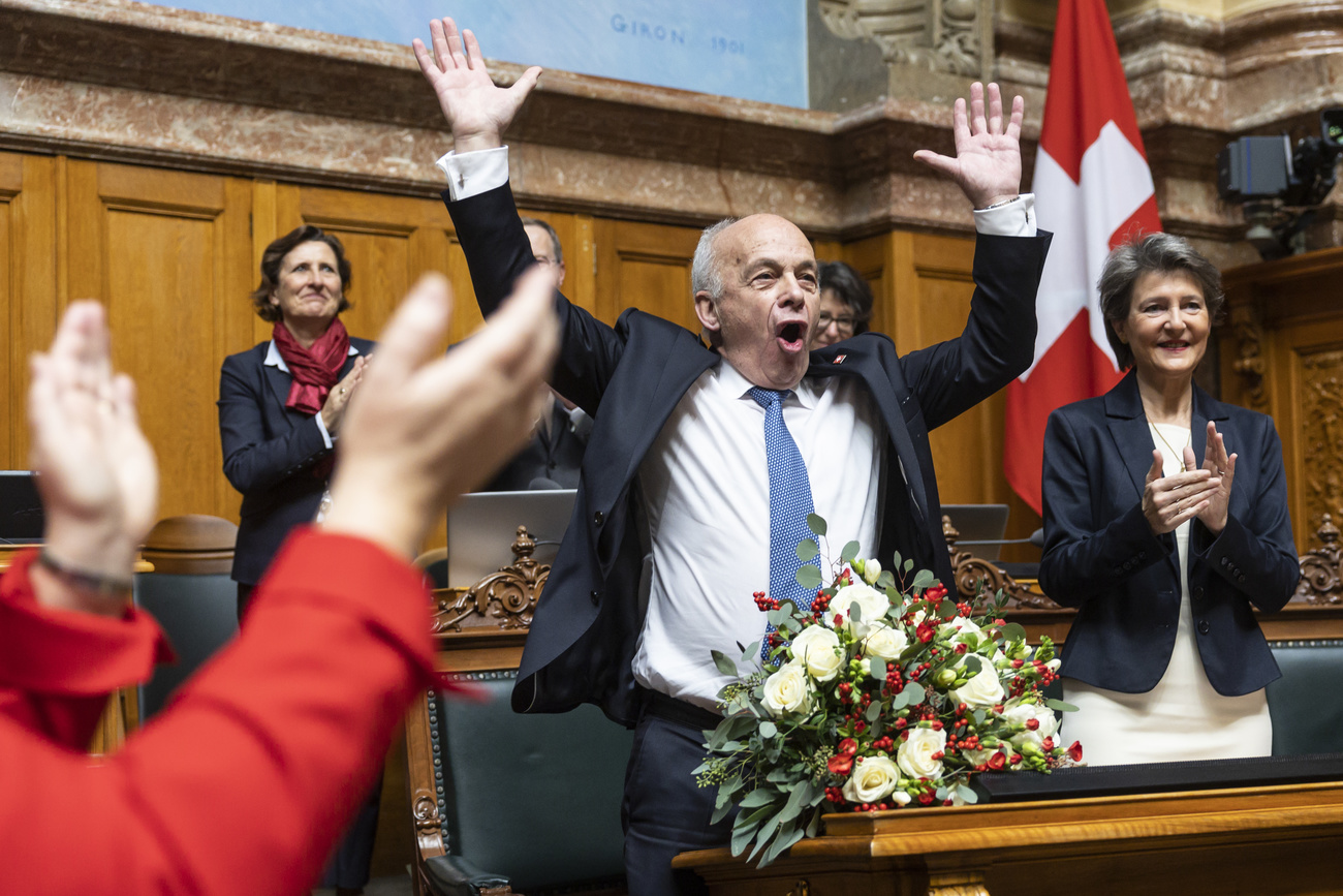 Il Consigliere federale uscente Ueli Maurer, a sinistra, alza le braccia al cielo accanto a Simonetta Sommaruga.