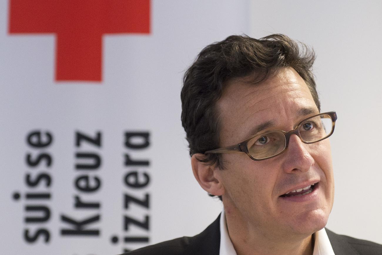 Homme posant devant le sigle de la Croix-Rouge