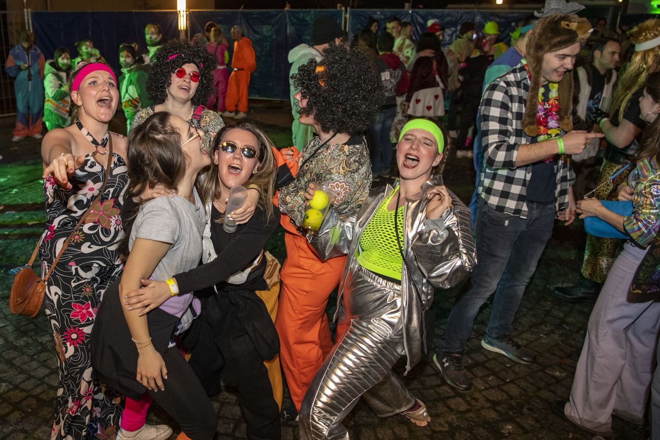 Personas con vestidos de carnaval se abrazan.