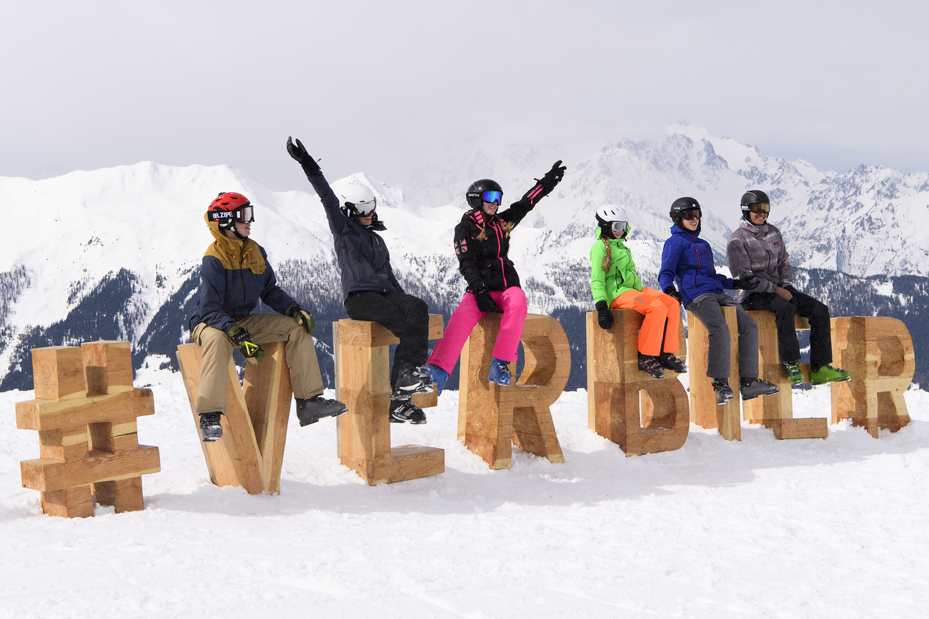 Des skieurs et skieuses posent autour d un panneau Verbier