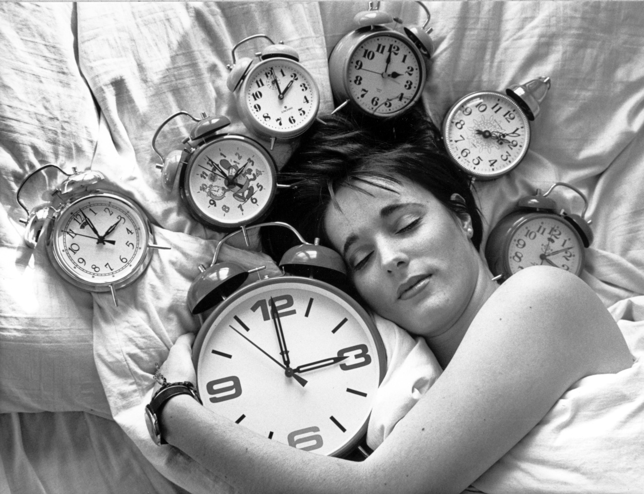 Una donna a letto con tante sveglie con ore diverse