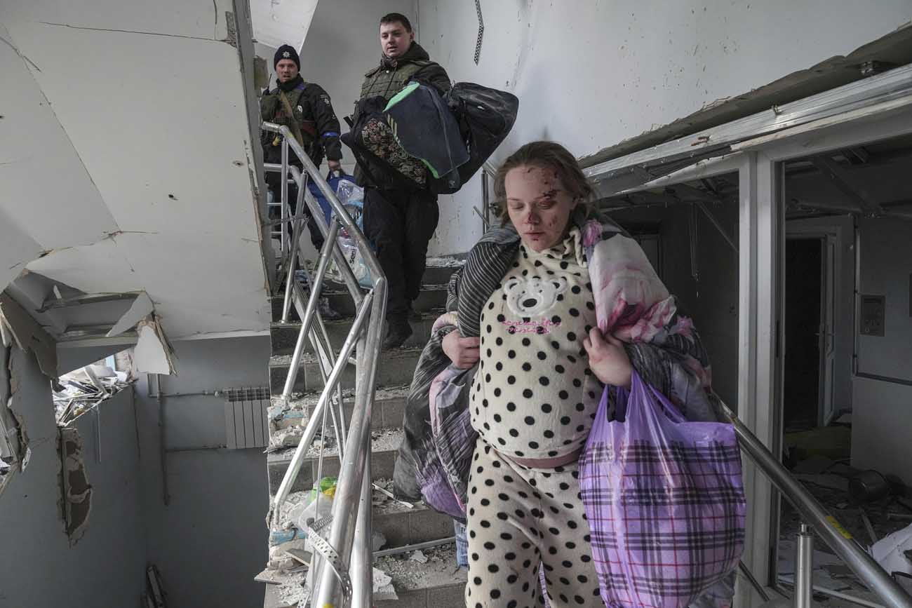Hochschwangere, verletzte Frau auf zerbombter Treppe