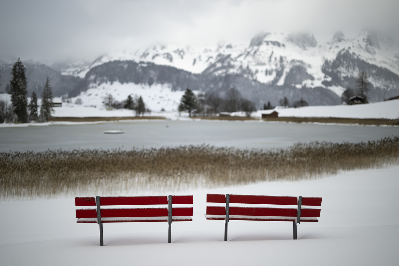 seats by lake with mountains in background in Switzerland.