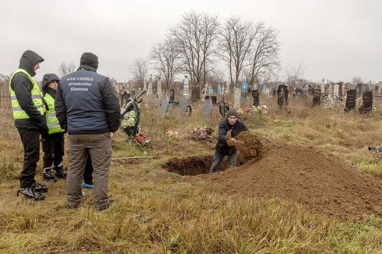 Personas en un cementerio. Una de ellas abre una fosa