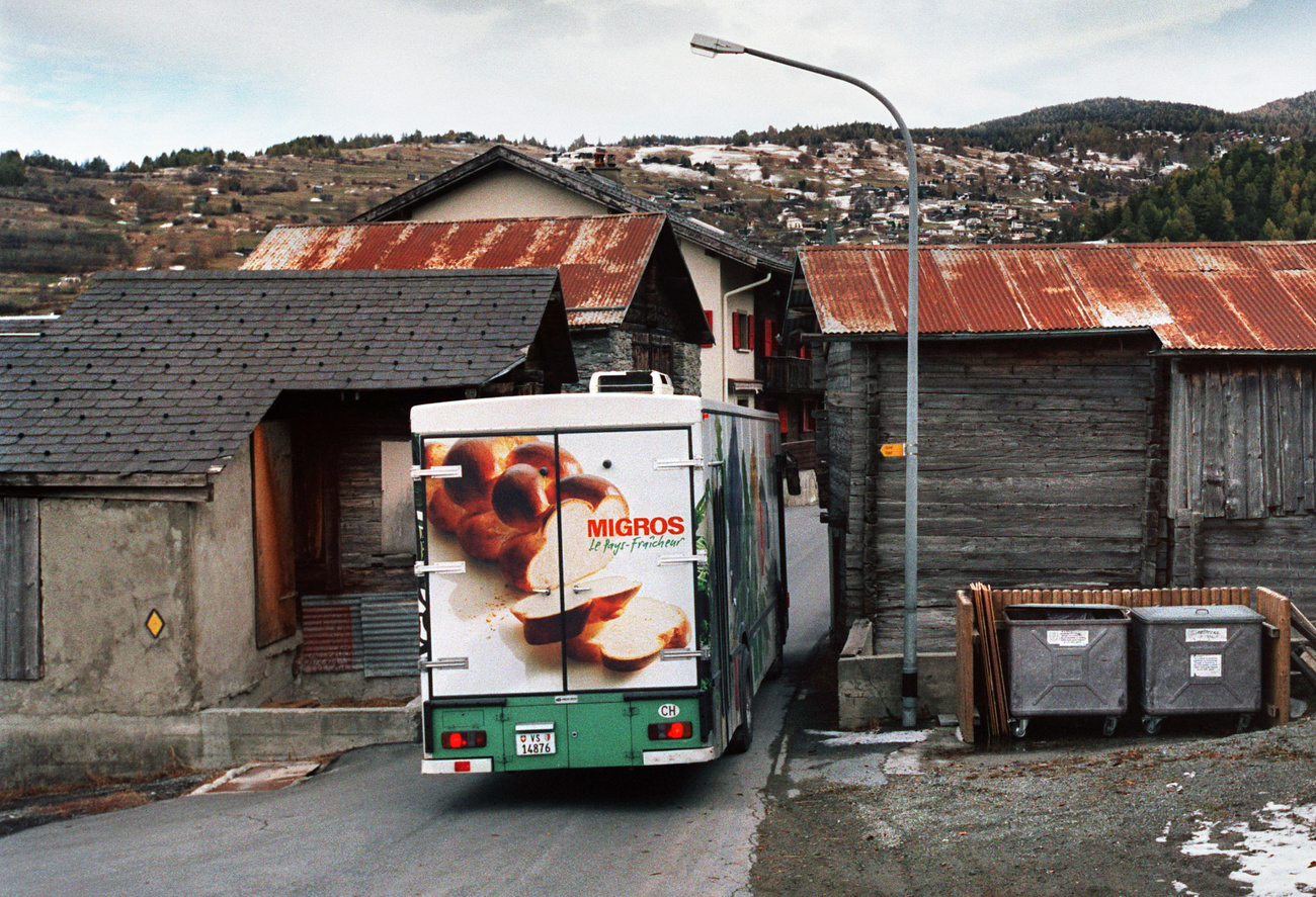 Camión de Migros entrando en un pueblo de montaña en el Valais