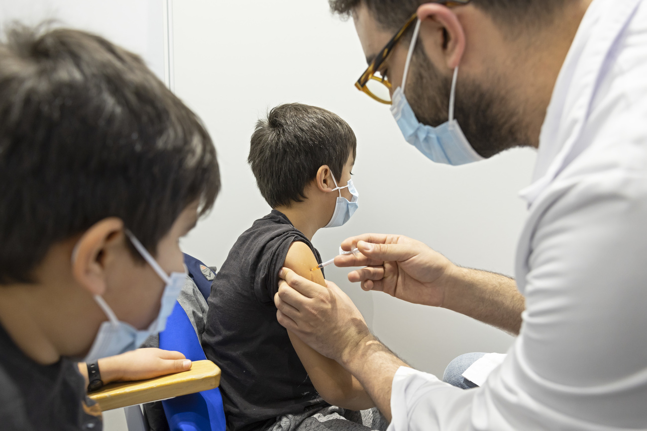 Un niño recibe una vacuna, otro observa.