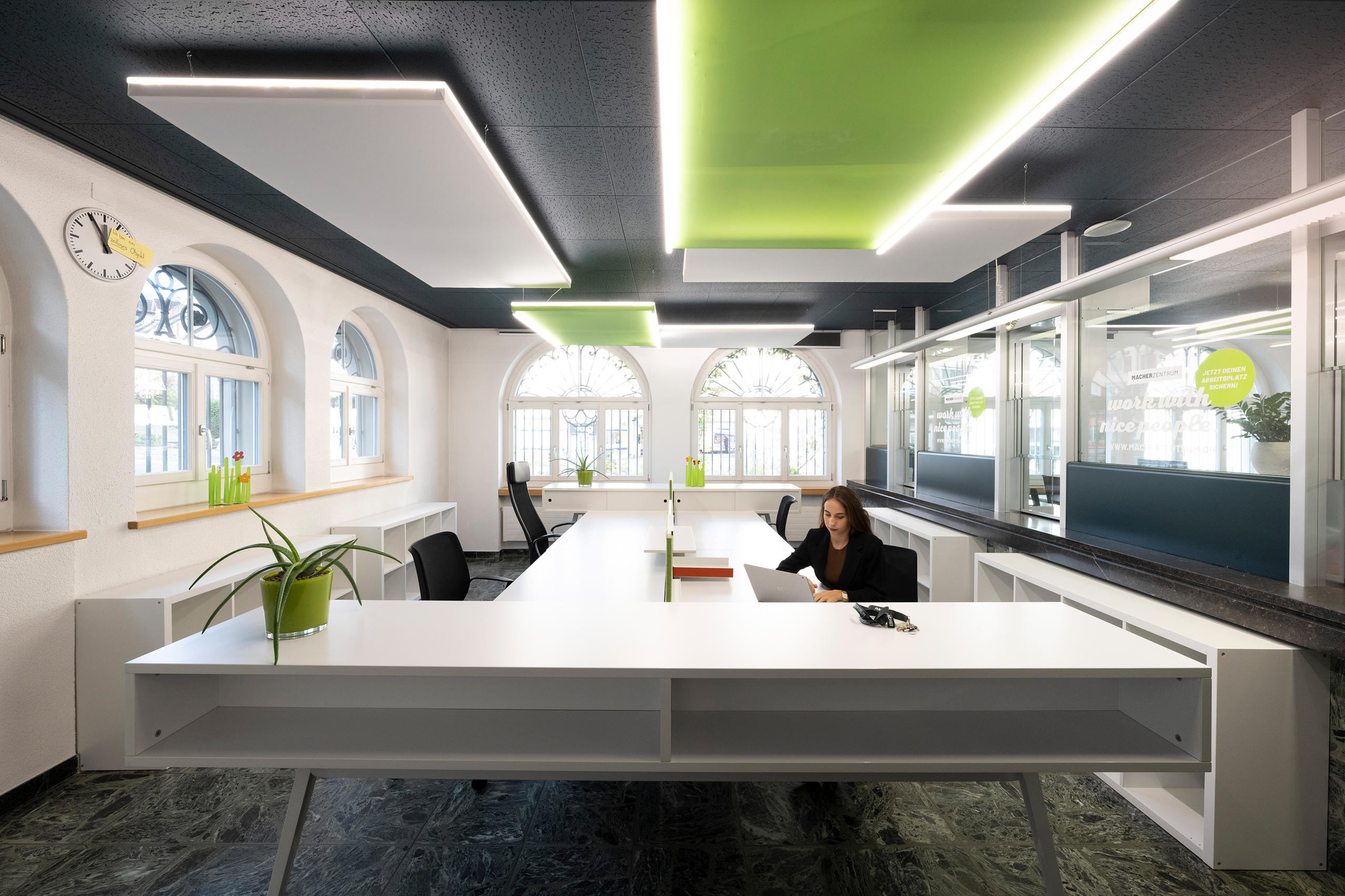 امرأة تعمل على حاسوب داخل قاعة فسيحة ومضيئة