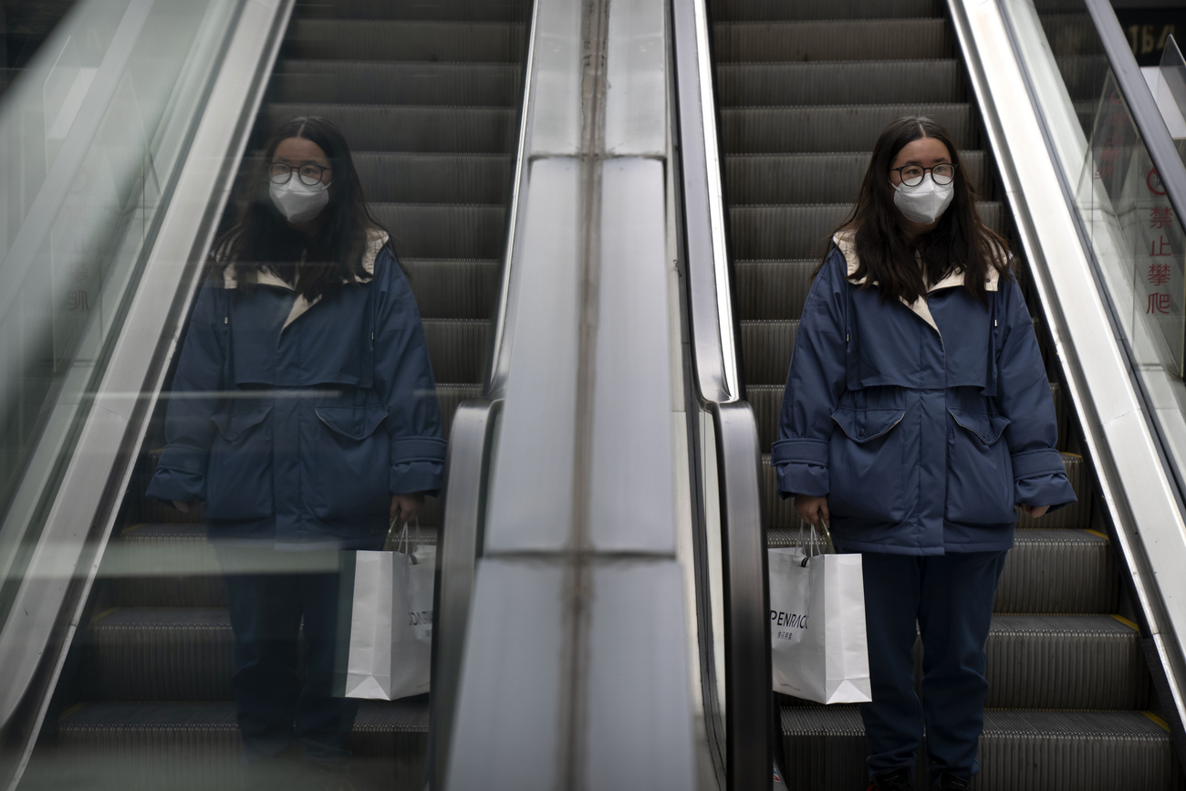 Una chica con mascarilla baja unas escaleras eléctricas.