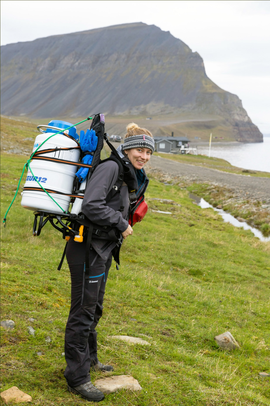 Frau mit Rucksackrahmen, auf dem ein Trockenversandbehälter angezurrt ist