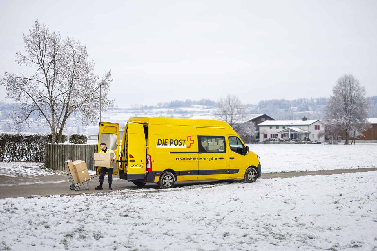 Un furgone della Posta nella neve con un postino alle prese con dei pacchi.