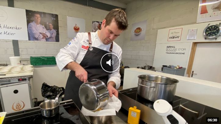 Koch, der in der Küche sorgfältig Flüssigkeit aus einer Pfanne abschüttet