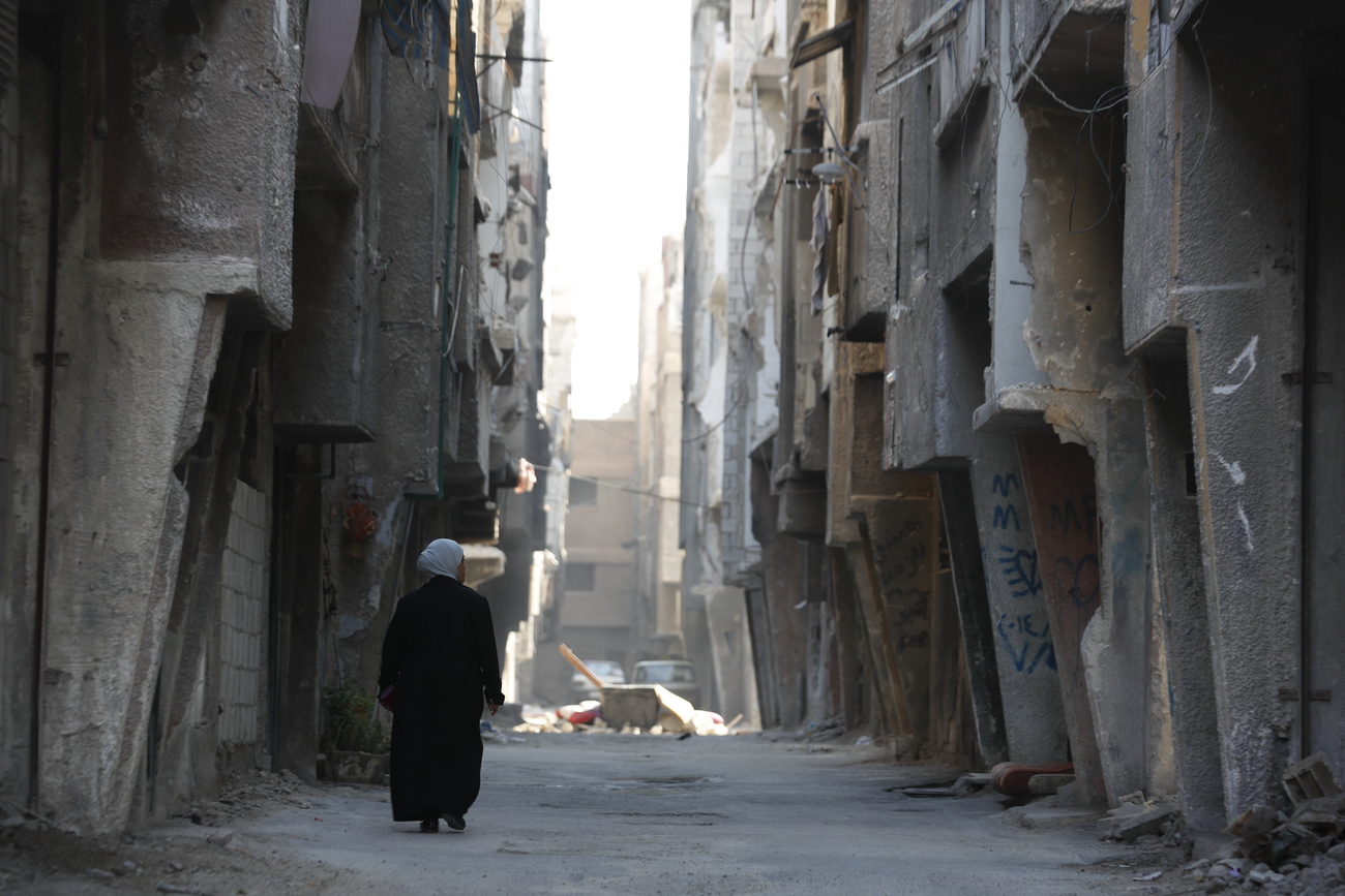 امرأة تمشي في مخيم اليرموك في دمشق