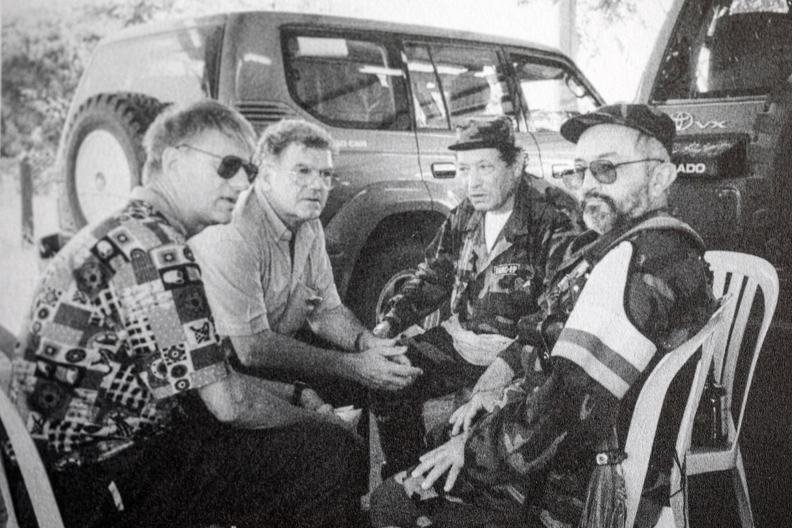 Vier Männer, die auf Plastikstühlen vor einem Fahrzeug sitzen