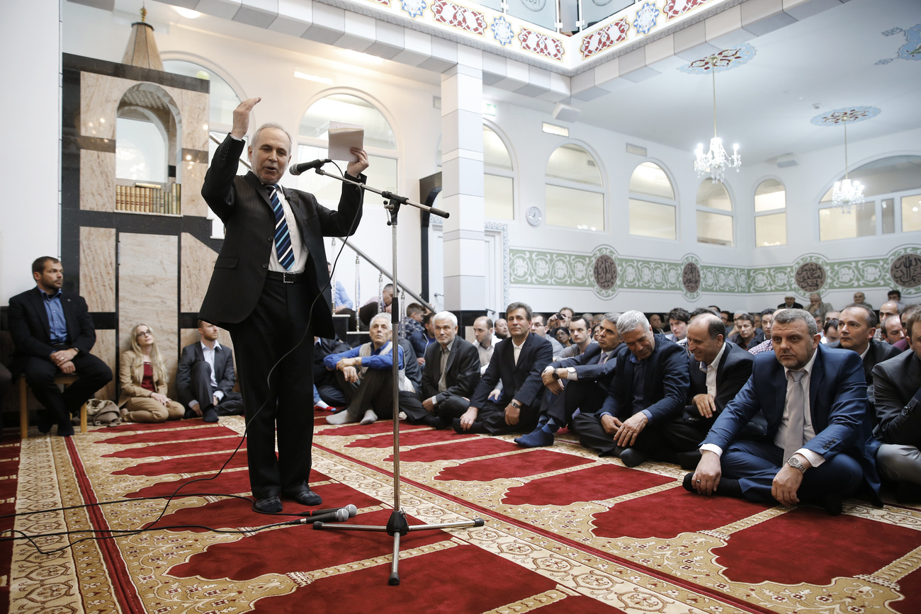 رجل يتحدث أمام مصدح داخل مسجد