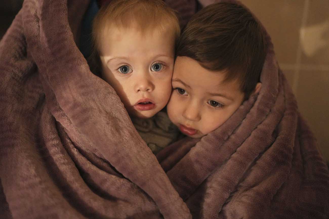 طفلان صغيران يتدثران بغطاء صوفي