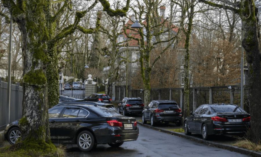 parkierte schwarze Limousinen entlang einer schmalen Strasse mit vielen Bäumen