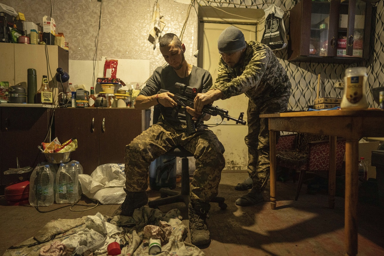 Two Ukrainian soldiers check a gun