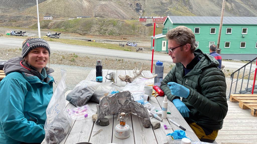 Zwei Menschen an einem Holztisch mit verschiedenen Instrumenten zur Analyse von Proben