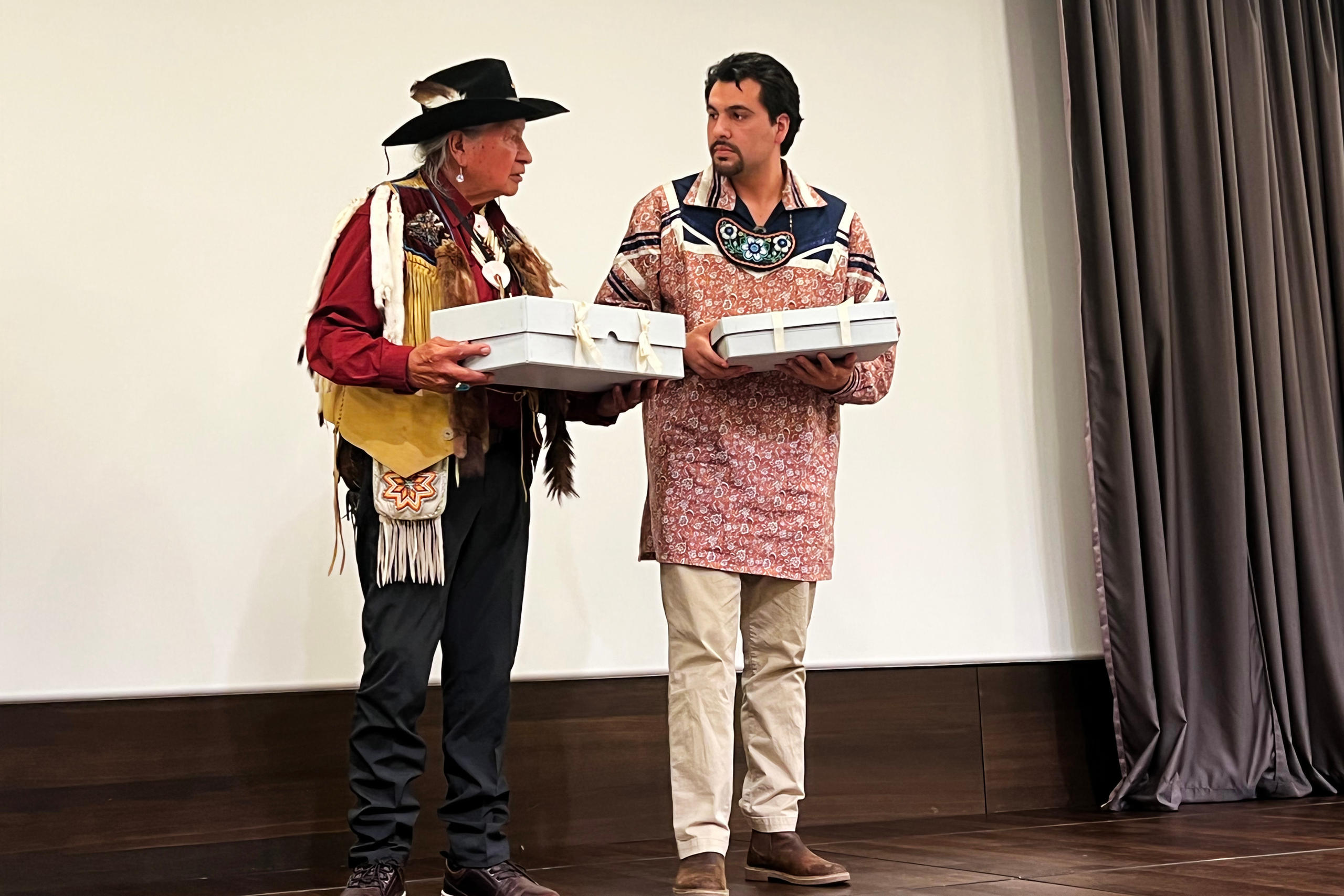 Two First People representatives holding scared objects in boxes