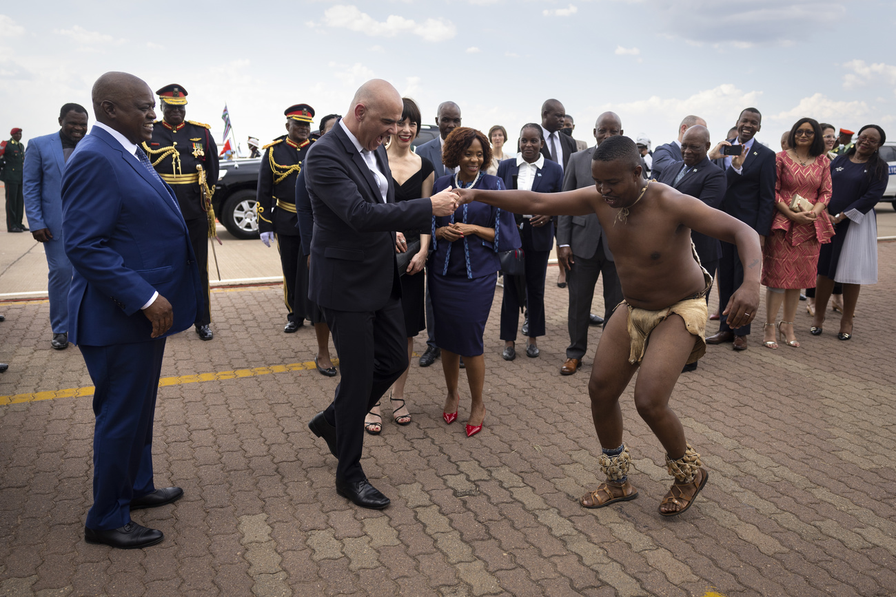 Un homme blanc faisant quelques pas de danse parmi des officiels en Afrique