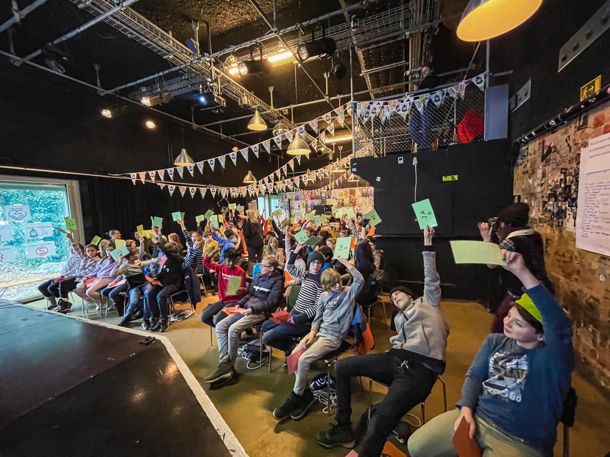 Kinder im Kipa Luzern halten bei einer Abstimmung grüne Karten hoch, die Ja bedeuten